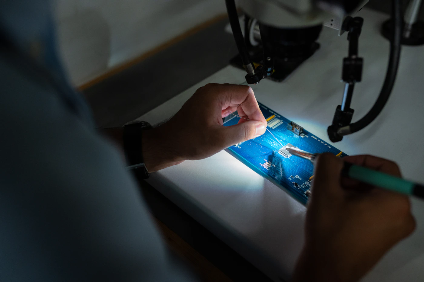 A technician working on electronic components under a microscope